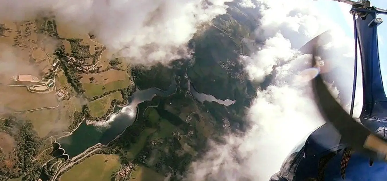 Lac sinueux vu depuis l'autogire, montagnes en partie sous les nuages