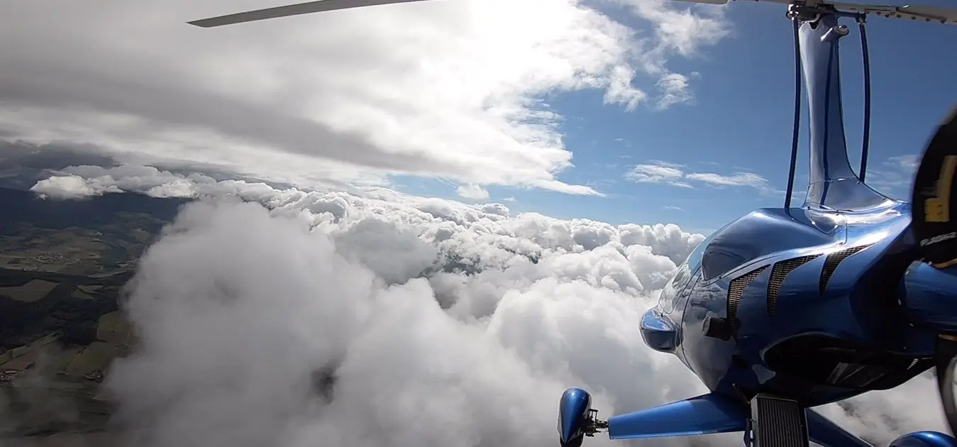 Un autogire survole une mer de nuages au-dessus de la campagne
