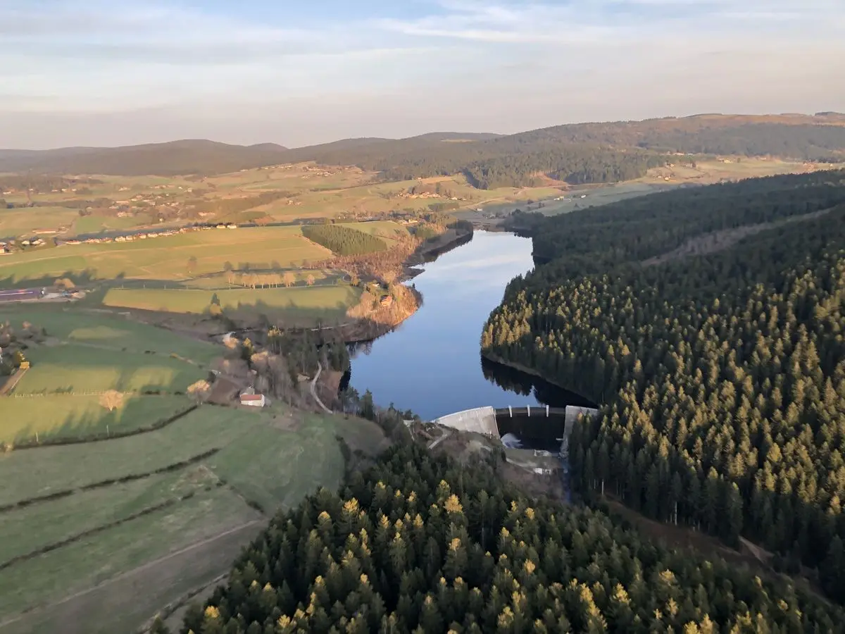 Vue aérienne d'un lac de retenue et de son barrage entourés de forêts
